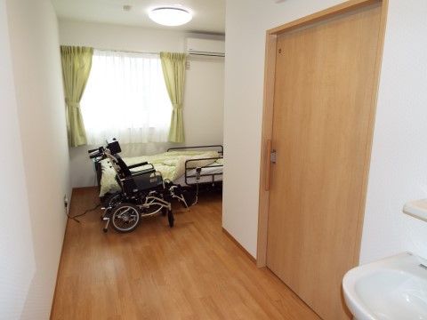 窓には若葉色のカーテンが留められており、明るい自然光を室内に取り入れている。窓の手前にはベッドがあり、転落防止用の柵が取り付けられている。