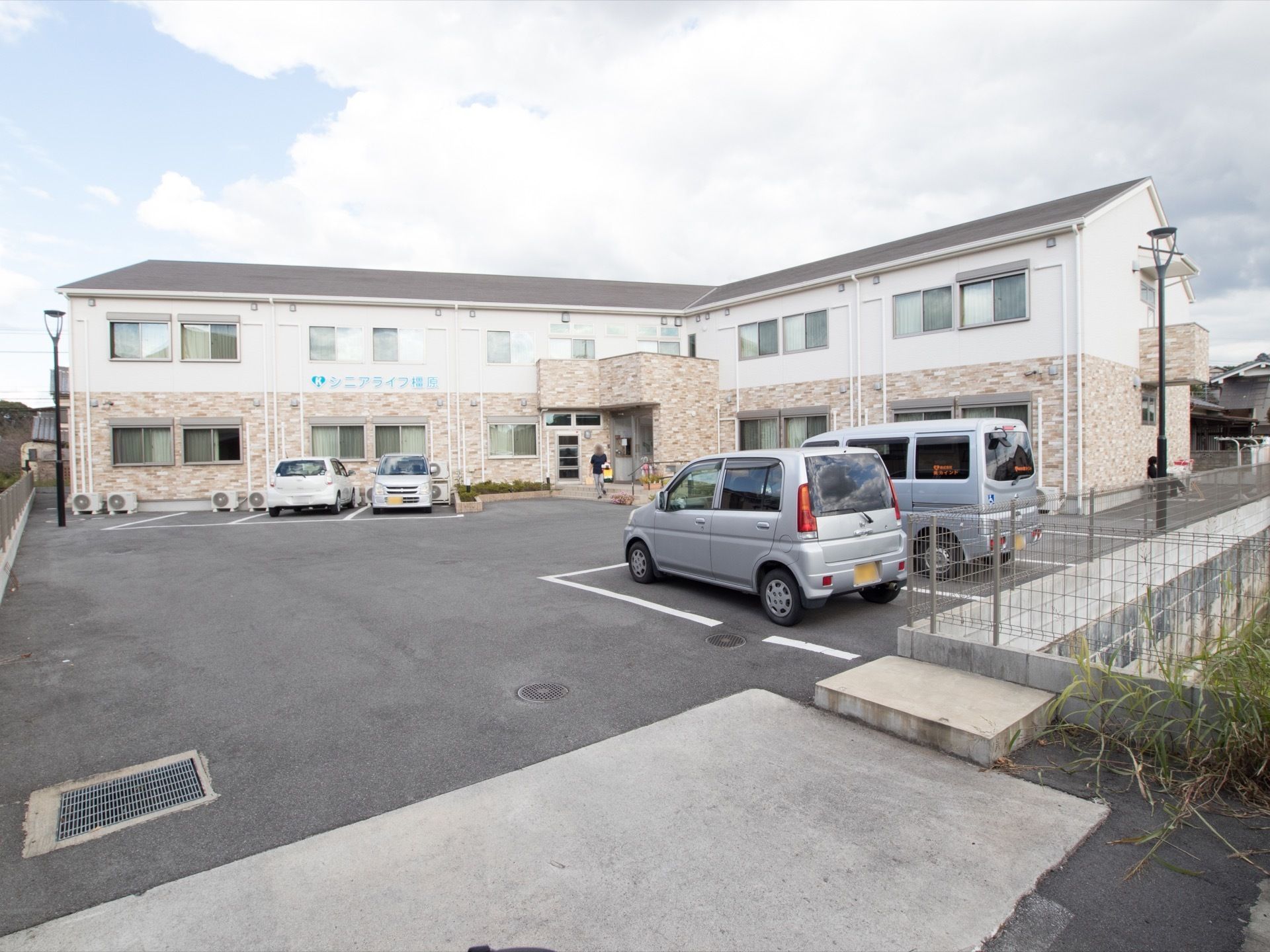 白い壁とレンガ模様が上下に分かれコントラストの美しい2階建ての施設である。L字型の建物には正面玄関の上の2階部分中央にテラスがある