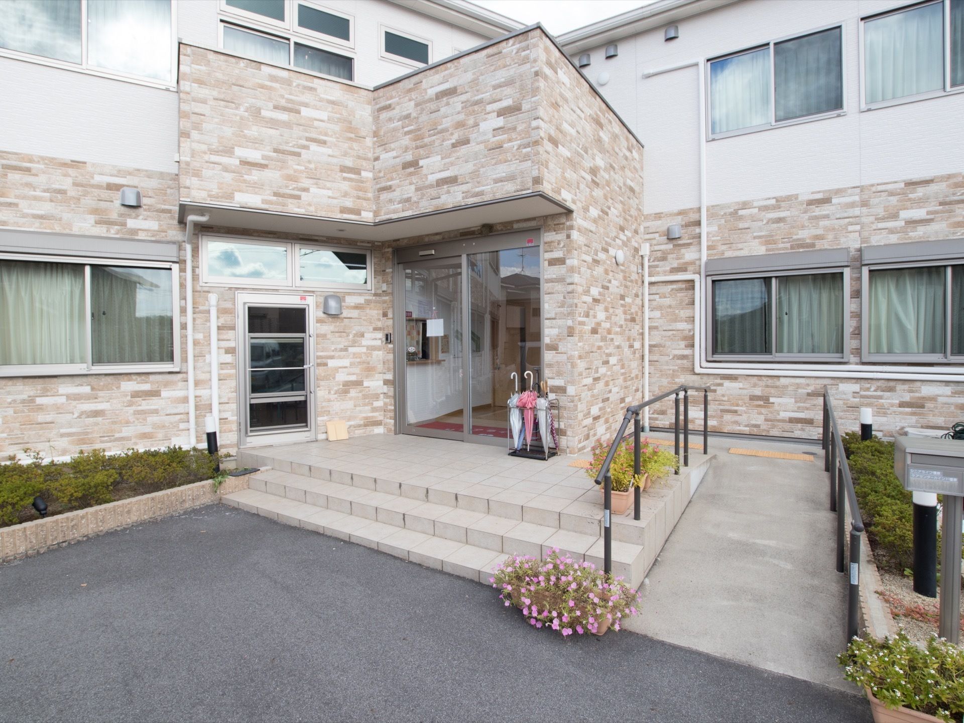 建物の中央にある玄関わきに手すりのついたL字の右側建物に垂直に緩やかなスロープがある。玄関正面は3段の広い階段になっている。