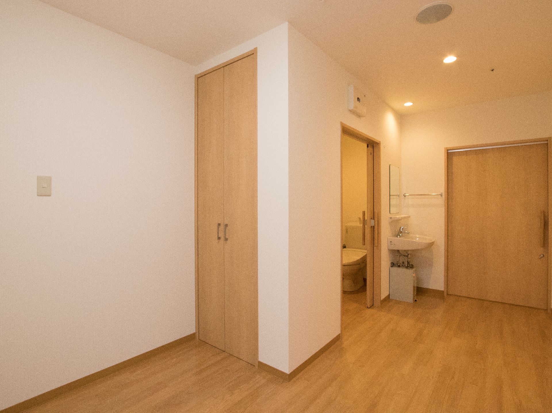 入口ドアの横に洗面台と個室トイレがあり、収納スペースが確保されている部屋
