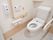 トイレの壁にトイレットペーパーや手すりだけでなく、緊急時用のベルや便器を掃除できるクリーナーがある。