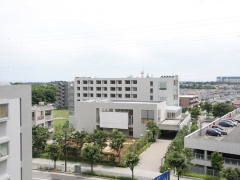 鉄筋コンクリート造りの白い外壁で、７階建ての大きな建物。玄関前は歩道からまっすぐ平らに舗装されている。緑に囲まれた中庭がある。