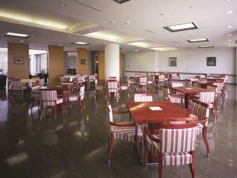 ストライプ模様の肘掛け椅子と机が並んだ、広々とした食堂。壁と天井は白く、床は落ち着いた色のフローリングになっている。