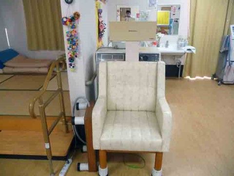 ベージュの電位治療器が設置されている。左側には畳スペースがあり布団を敷いて休むこともできる。移動時に必要な手すりもある。