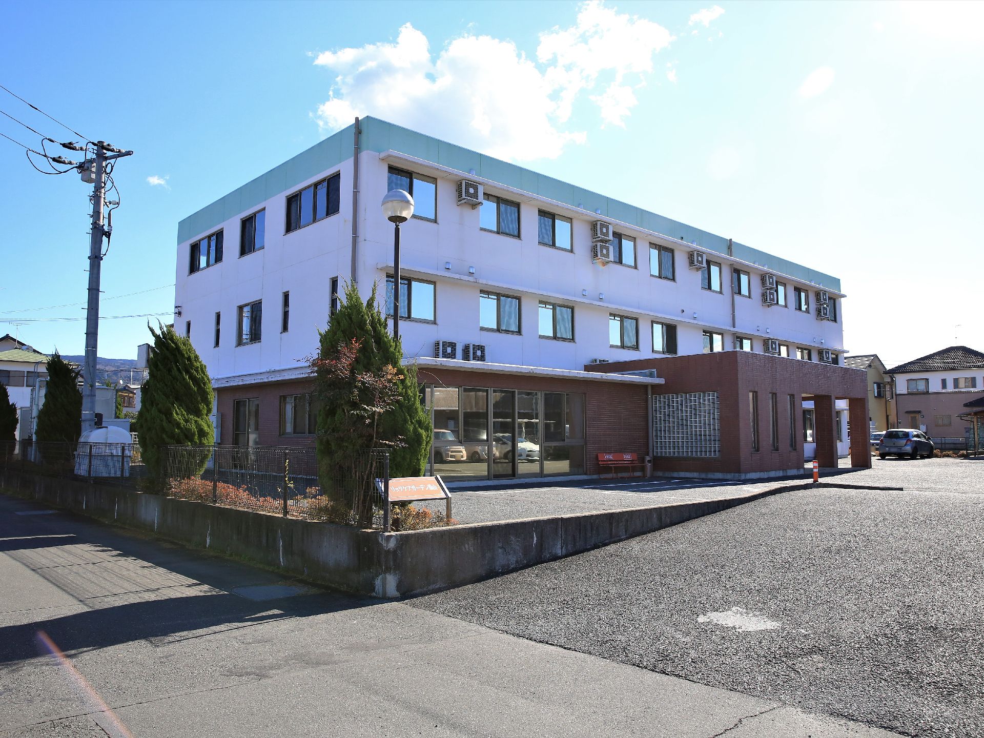 道路からの勾配は緩やかで、スムーズに施設入口へ進める。建物周囲には、植え込みや駐車場が完備されている。
