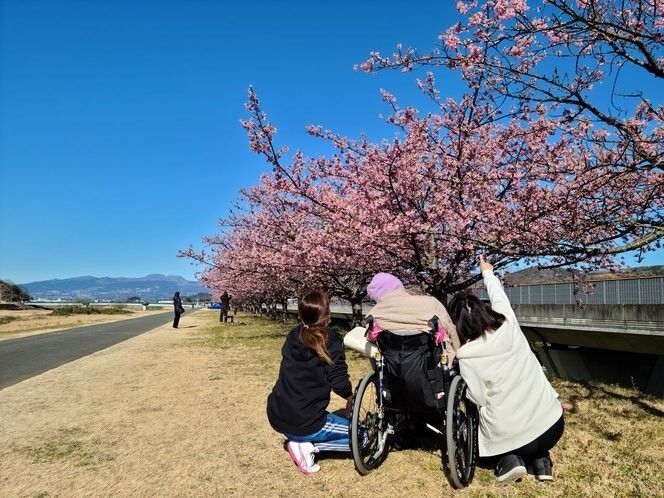 窓の前に並んで出し物をする女性を見学している入居者様