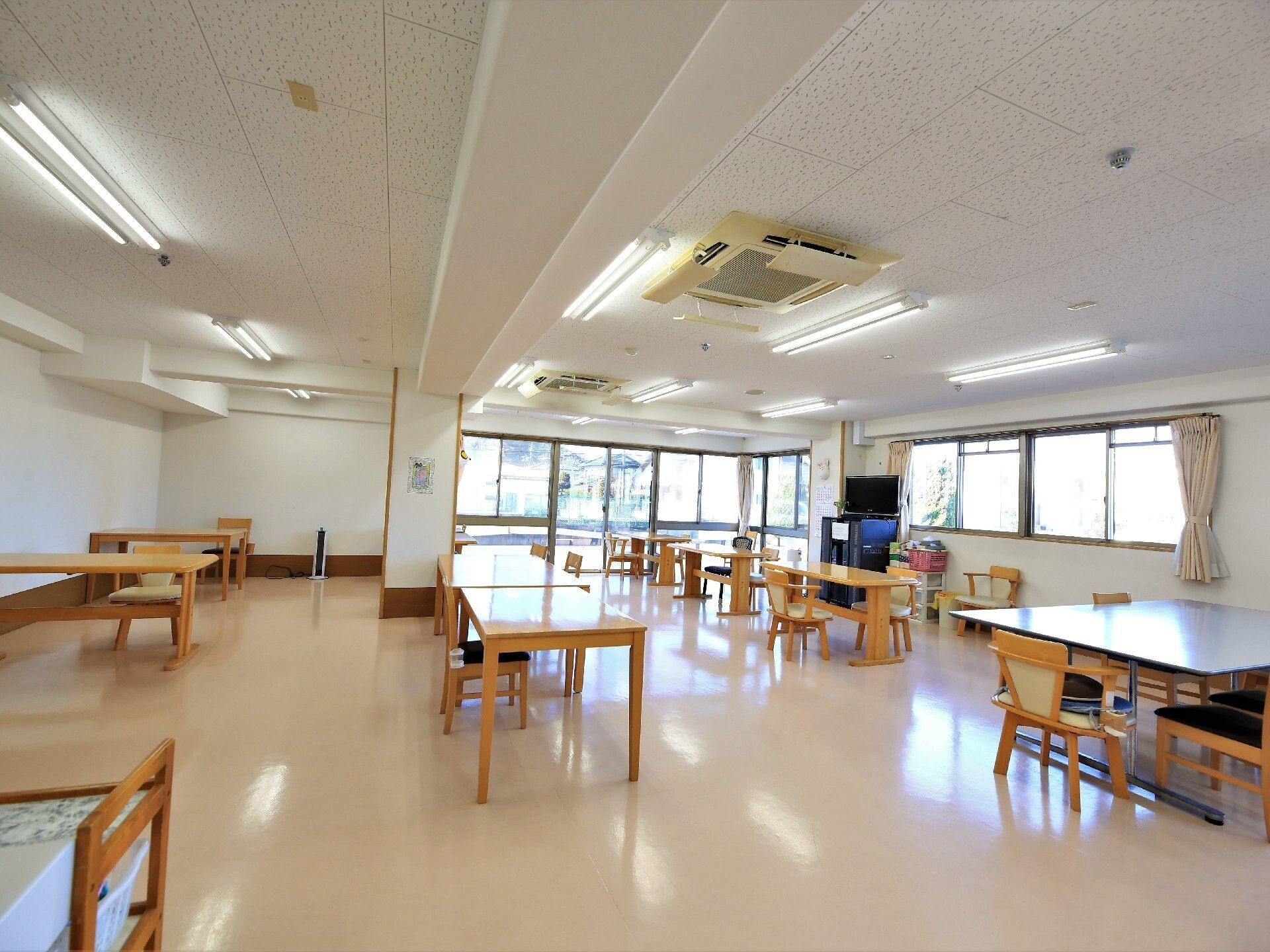 文字の書かれた団扇を持った施設のスタッフが、入居者様方とコミュニケーションをとっている。入居者様方は椅子に座り、落ち着いて話を聞いている。