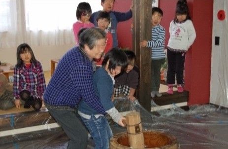 子供と一緒に杵を持って、餅つきをしている入居者の女性