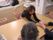 ピンク色の椅子に座って、入居者の両手をとって笑っている女性スタッフ