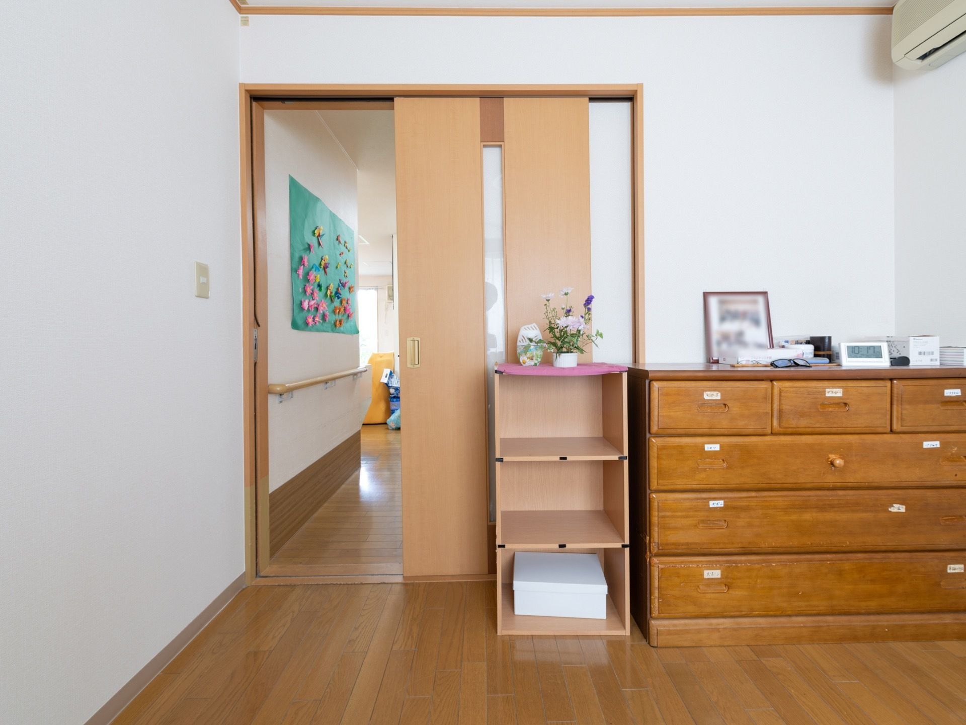 居室への入口はスライド式の木製扉である。出入口には段差がない。居室に入ってすぐの位置に、収納用のチェストや箪笥が備わっている。