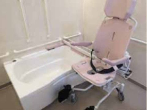 白を基調とした清潔感のある浴室である。洗い場には浴室用の車椅子が準備されており、シートベルトが取り付けられている。
