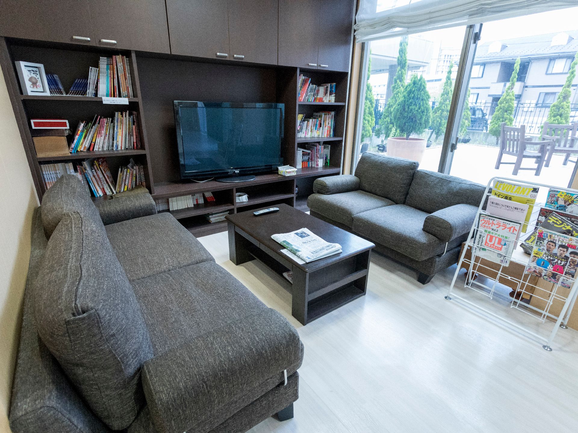 中央にテーブルとソファが置いてある。奥にはテレビが置かれている。テレビの周辺は本棚になっており、多くの本が並んでいる。
