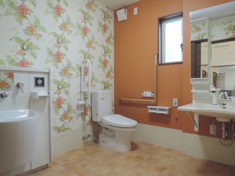 白い壁に大きな花の柄が描かれている、広々としたトイレ個室