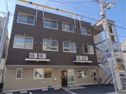 向かって右側に外階段が設置されている、三階建ての施設外観
