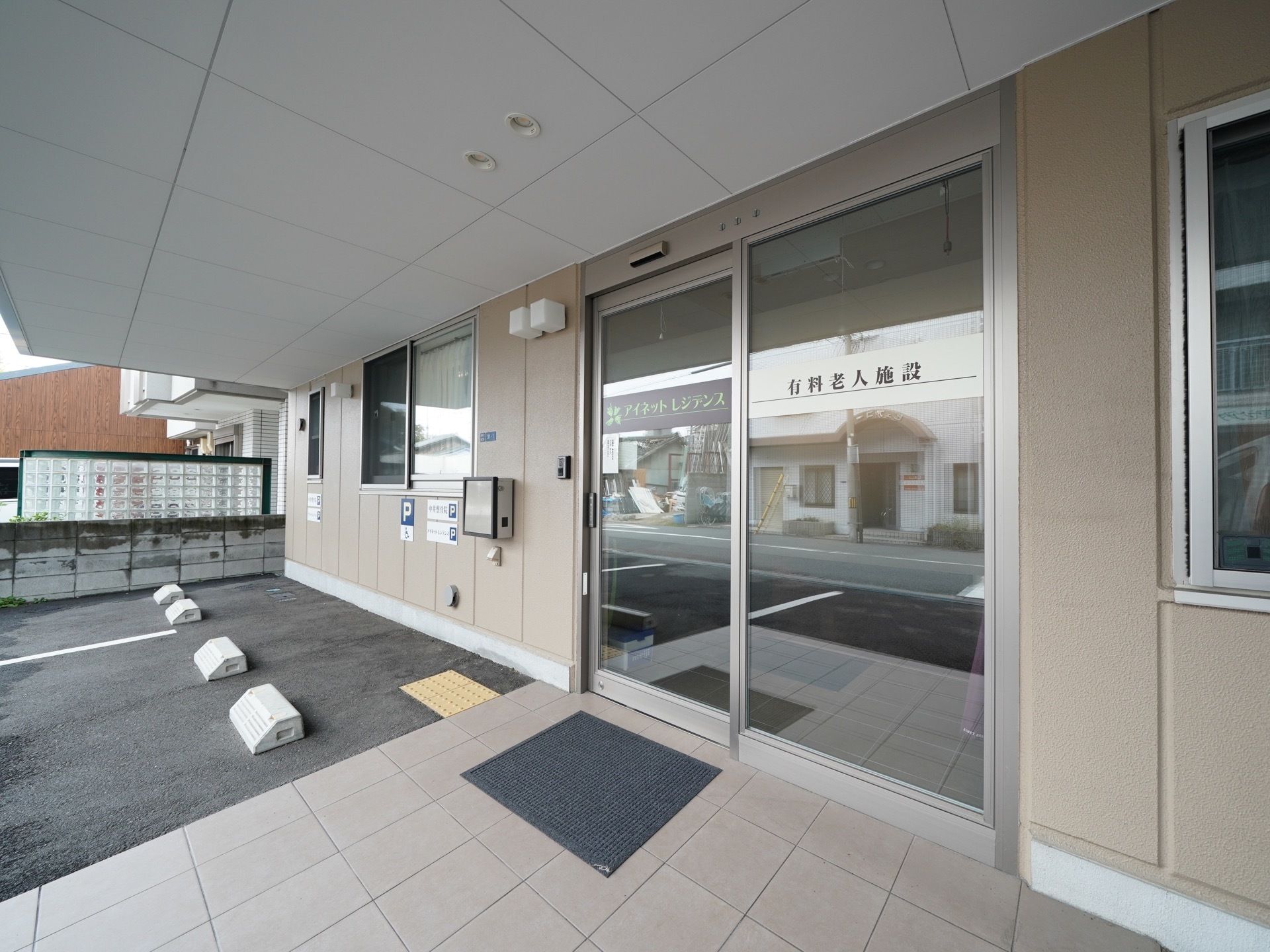 建物の中央に全面ガラス張りの玄関ドアが設置されている。ドアは自動ドアとなっている。玄関脇には駐車場が設置されている。