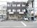１階はクリーム色、２階と３階はダークグレーの外壁の３階建ての建物である。建物の右側に外階段が設置されている。施設の前に駐車スペースがある。