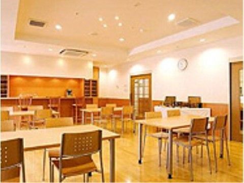 白と木目調の明るい部屋に複数のテーブルセットが置かれている。地域の方々と交流をするセンターとなっている。
