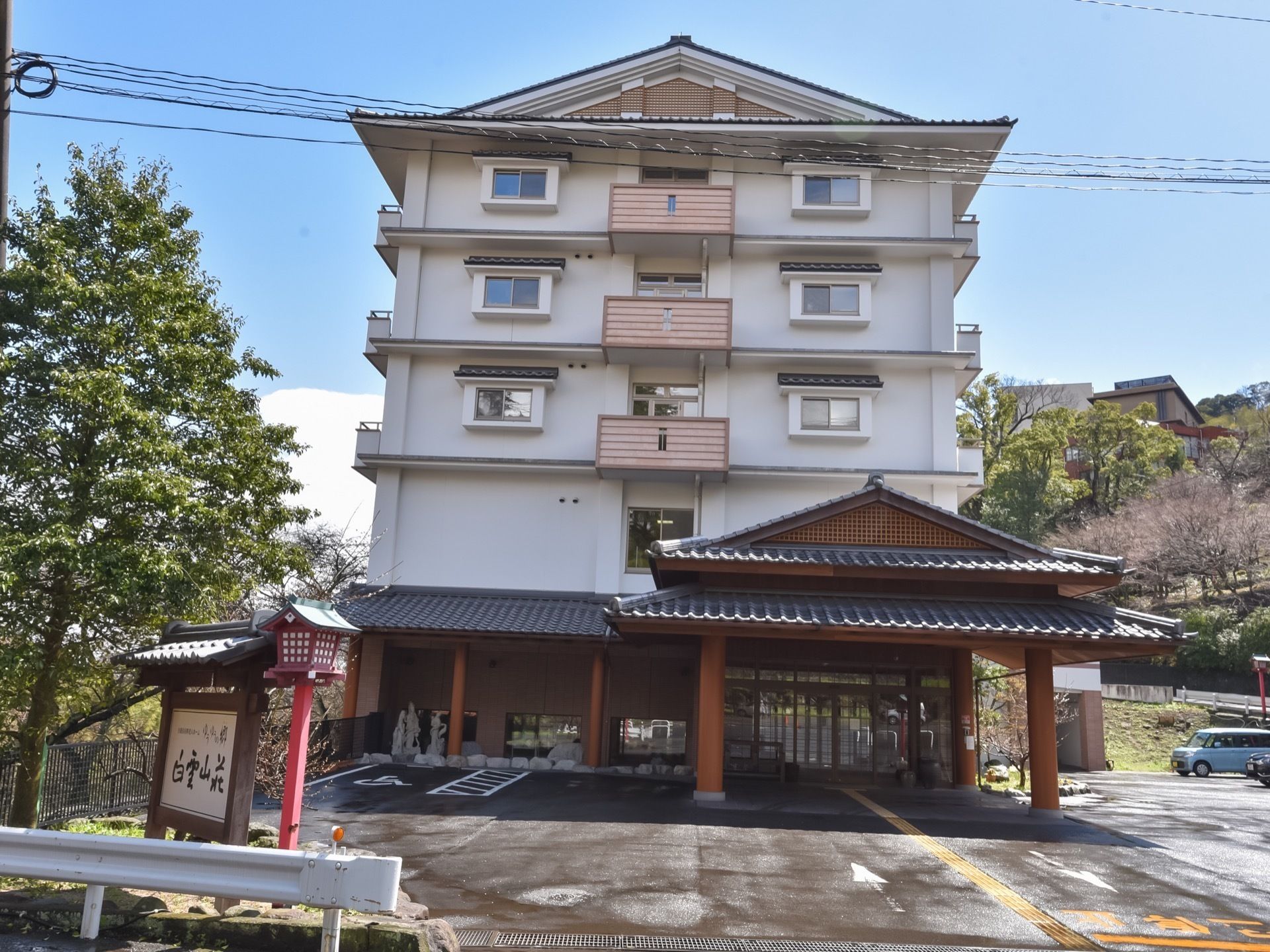 和風旅館のような佇まいの５階建ての施設である。建物横には、広い駐車スペースが設けられている。ポーチには、屋根付きのひさしが設置されている。