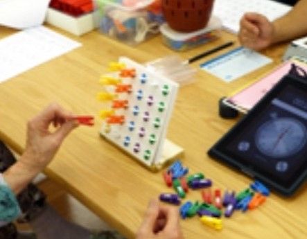 色鮮やかな小さな洗濯ばさみを使い、手先の訓練をする入居者