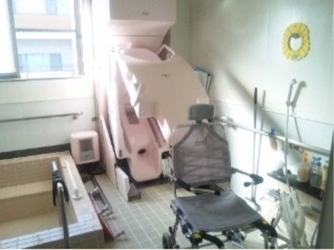白い壁際に、大きなピンク色の入浴補助器が設置されている浴室
