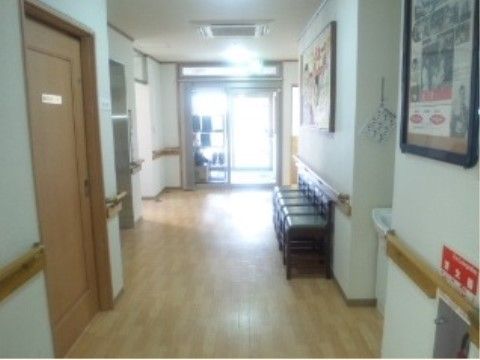 廊下の幅は広くとられ、両側の壁には隙間なく手すりが設置されている。掃除が行き届いた床は清潔に保たれ、一角には椅子が置かれている。
