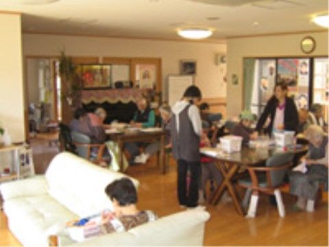 ソファーや椅子に座って、スタッフとともに手作業をしている入居者たち