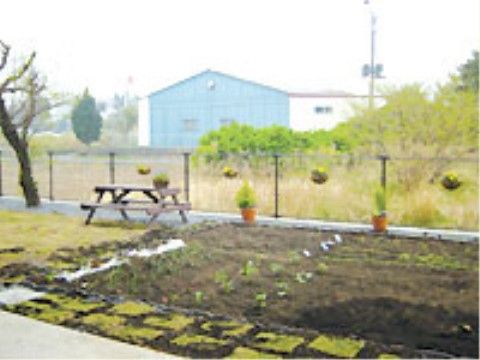ガーデニングをお楽しみいただける広々とした菜園が敷地内に設けられている。ガーデンテーブルがフェンス際に置かれている。