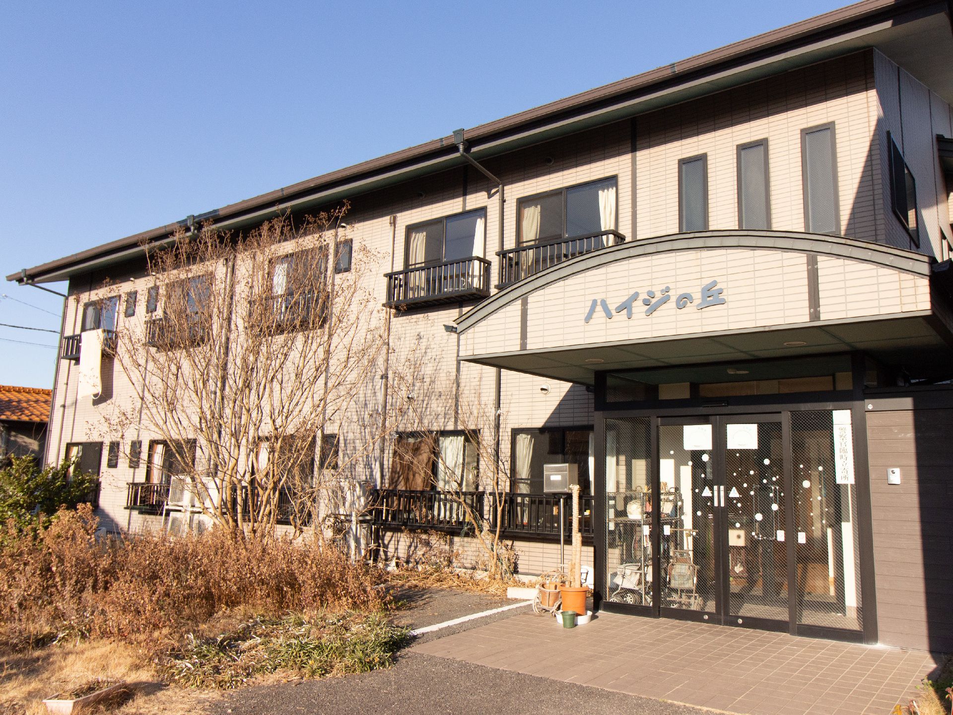 施設は２階建てアパート風の建物である。窓には、転落防止柵が設置されている。屋根付きのエントランスが設けられている。