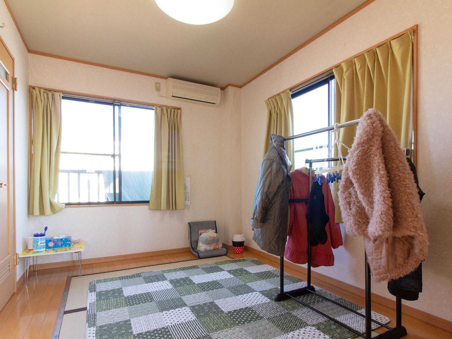 トイレとエアコン、照明が完備された和室タイプの居室である。床に敷かれた畳の上には、ハンガーラックが置かれている。