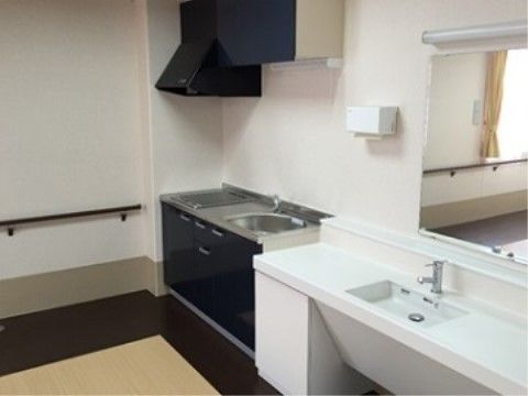 共有キッチンである。流しとIHコンロが設置されており、壁には手すりが備え付けられている。また、手洗い箇所には鏡が設置されている。