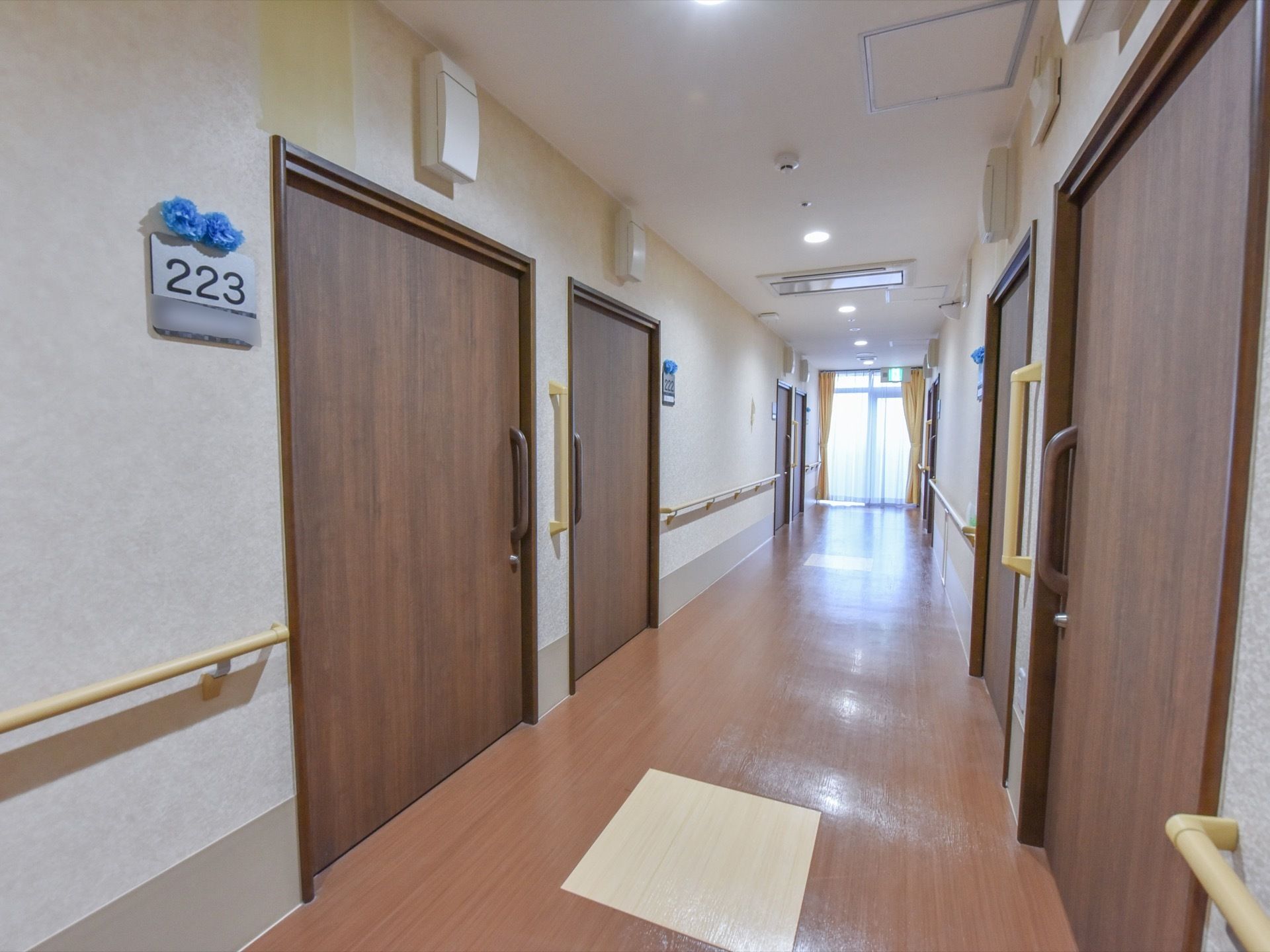 廊下に並ぶ部屋の前には、部屋番号のプレートがある。数字は大きな黒い文字で記されている。そして番号の上には、手作りの花がつけてある。