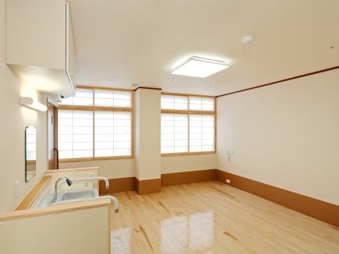 左側に手すり付きの洗面台が設置されている、フローリングの一室
