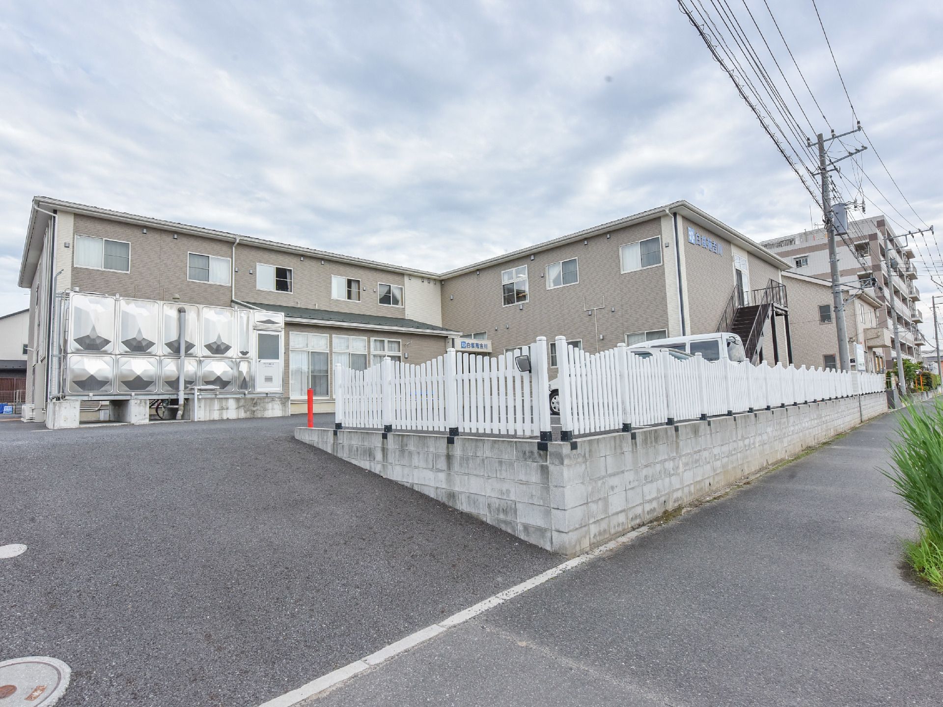 施設の建物は、道路より少し高い位置にあり、敷地への入口はスロープ状になっている。敷地の周囲には、白いフェンスが設置されている。
