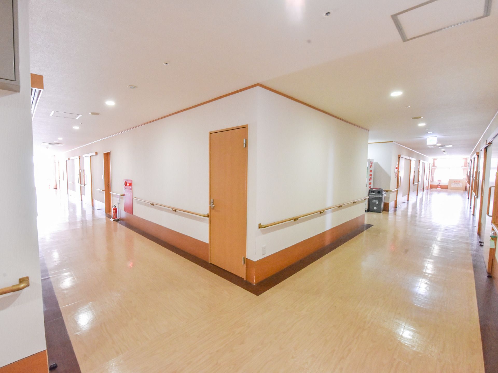 廊下が交差している場所。一角に、自動販売機と空き缶入れがある。廊下の壁には、手すりが取り付けられている。