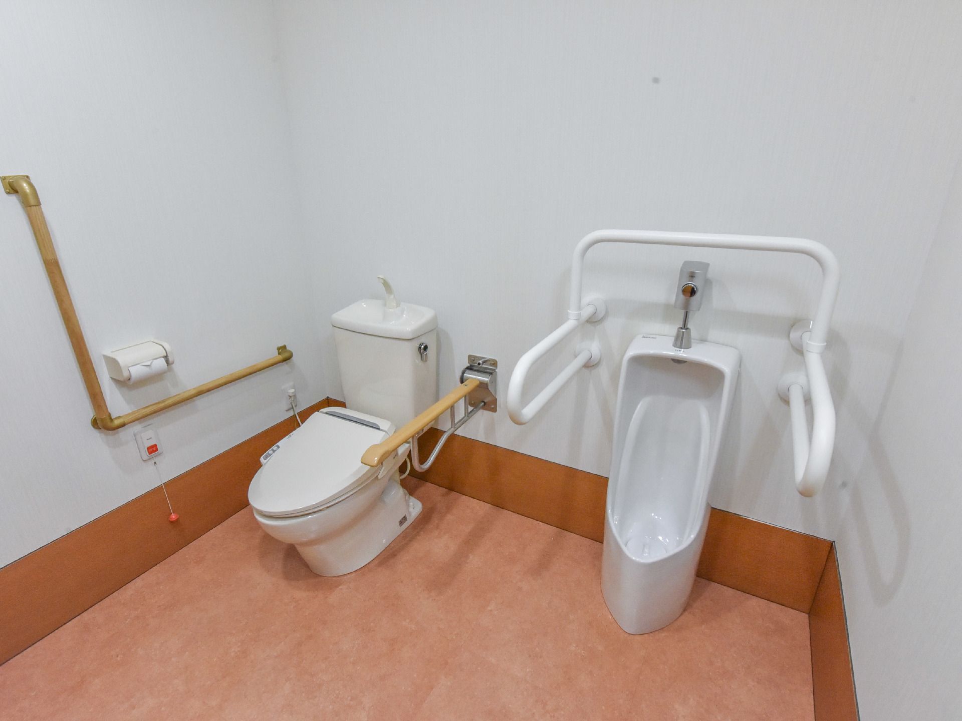洋式トイレと小便器が並んでいるお手洗い。小便器の周りを囲むように、手すりが設置されている。また、洋式トイレは壁にL字の手すりがある。