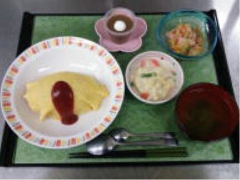 オムライス、サラダ、スープ、デザートの洋食メニュー。彩り鮮やかで見た目にも楽しく、食欲をそそる献立である。