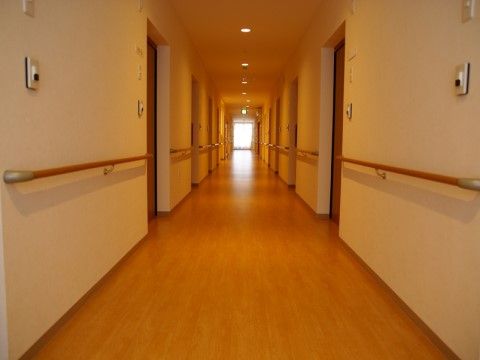 各個室につながるドアが並んだフローリングの通路。個室の入り口にはチャイムがあり、壁にはすべて手すりが付いている。