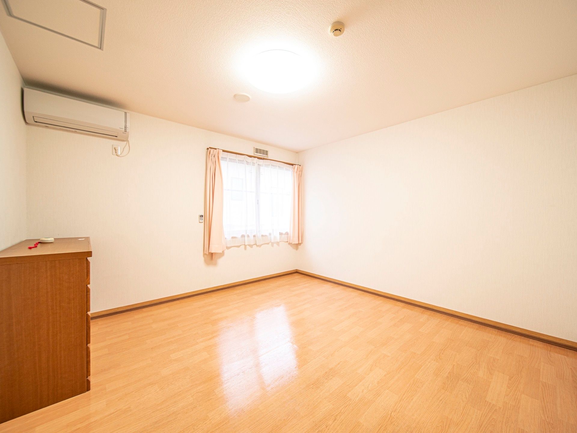 白い壁とフローリングの床になっている広々とした居室である。窓があるので、陽射しが差し込む明るいスペースである。