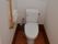 トイレは白い壁で清潔感のあるスペースである。手すりを壁にL字に設置しており、立ち上がる際に体を支えることができる。