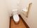 洋式トイレの便座のそばに手すりが設置されている。便座の前のスペースは広く取られている。緊急時にスタッフを呼べるブザーもある。