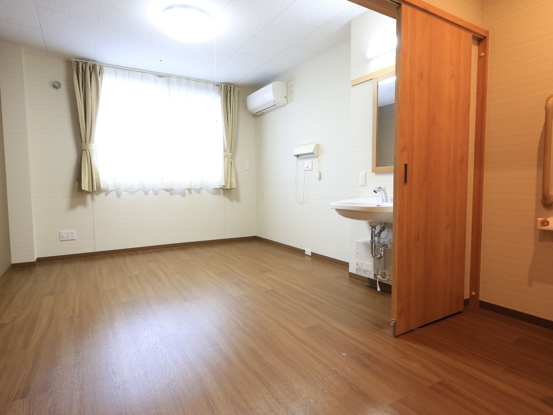 洗面台の近くには、ナースコールとともに照明器具が取り付けられている。頭上には、エアコンが設置されている。