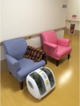 壁際にピンクと水色のソファーが設置されており、水色のソファー前に足のマッサージ機がある風景