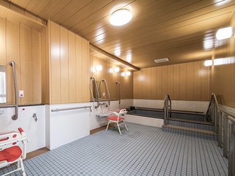 「リアンレーヴ入間」の浴室。広い浴槽にシャワーチェア、手すりを備え付けている。
