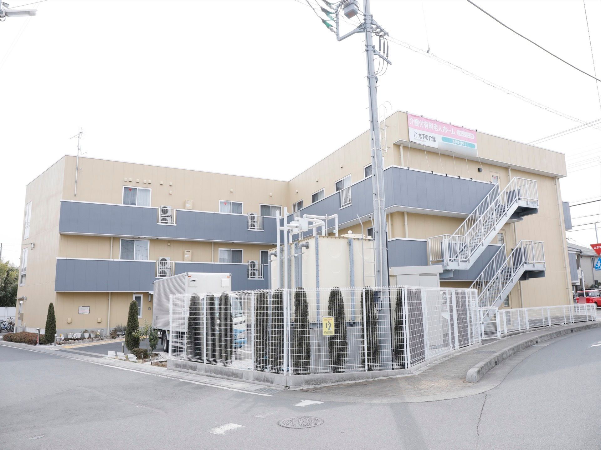 道路に面した敷地に立地している施設の外観。ベージュとグレーと基調とした落ち着いた雰囲気になっている。