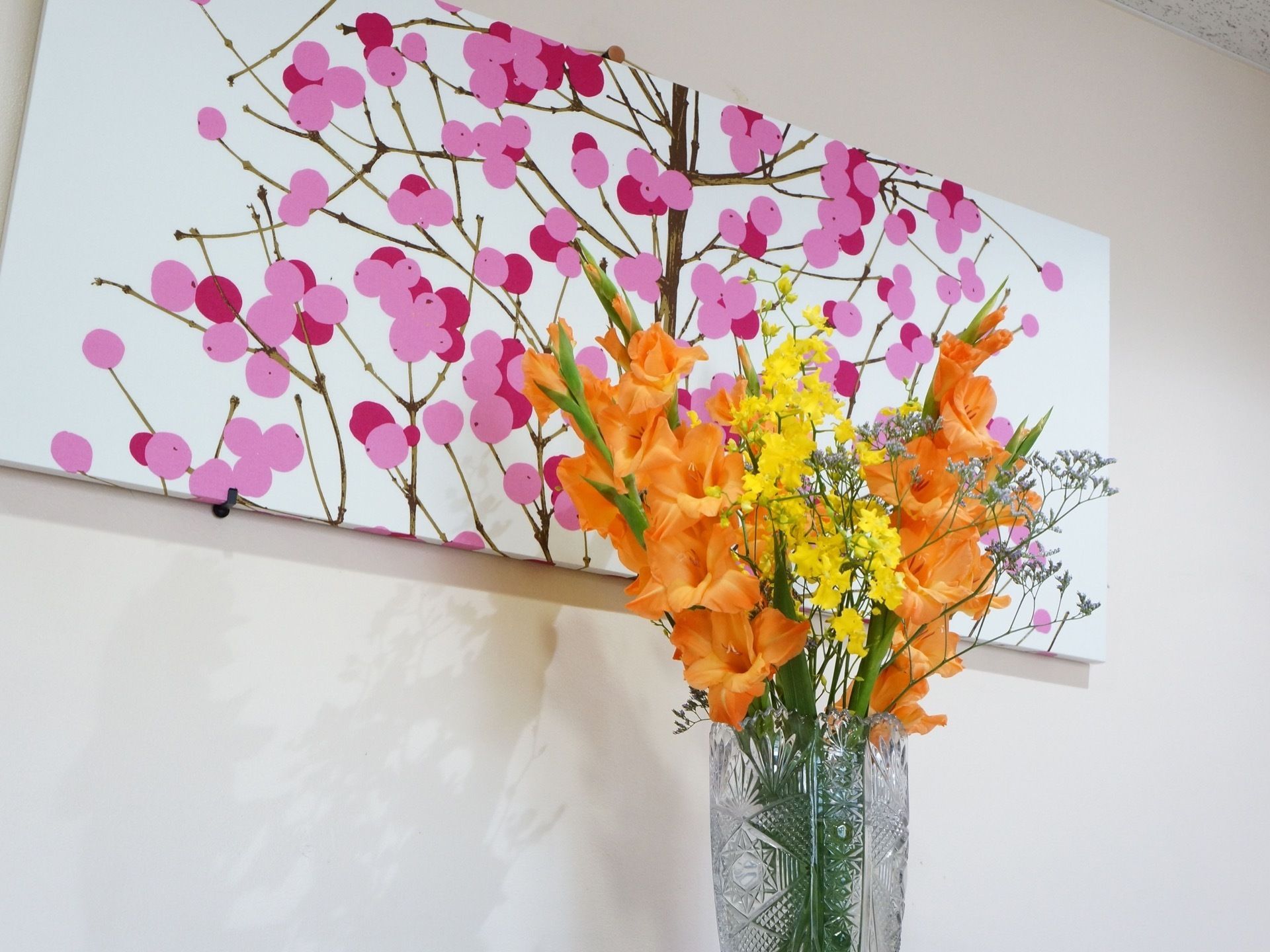 大きな花瓶に入れた花を飾っている。オレンジや黄色など鮮やかな色の花で華やかである。施設には多くの花が飾られている。