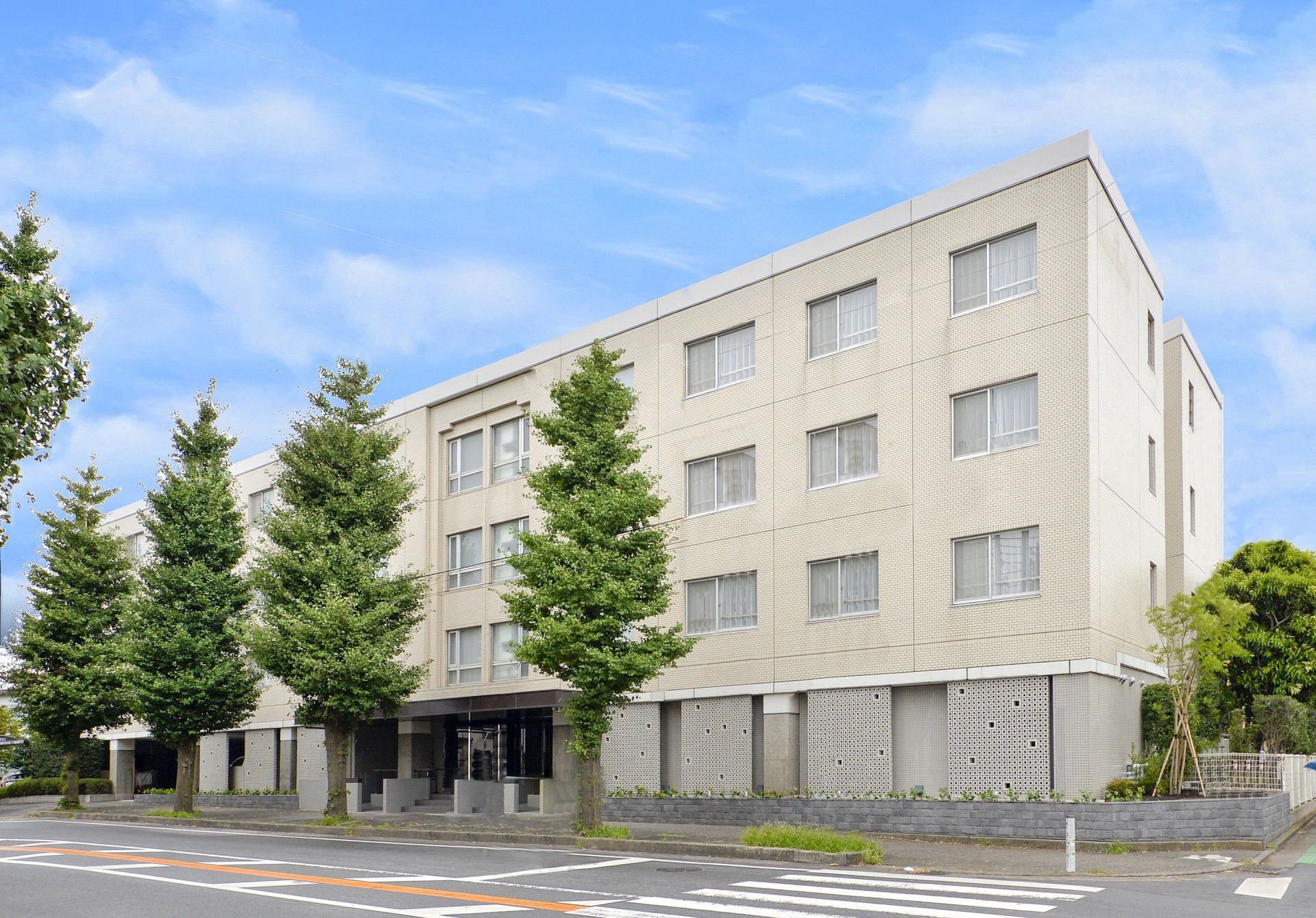 青空の下に建っている、四階建ての白く大きな施設外観