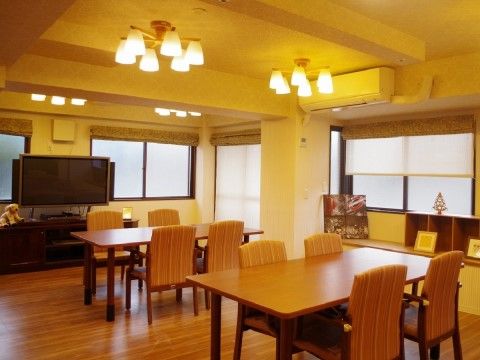 奥に大きなテレビがあり、その前にテーブルセットが二つ設置されているリビング