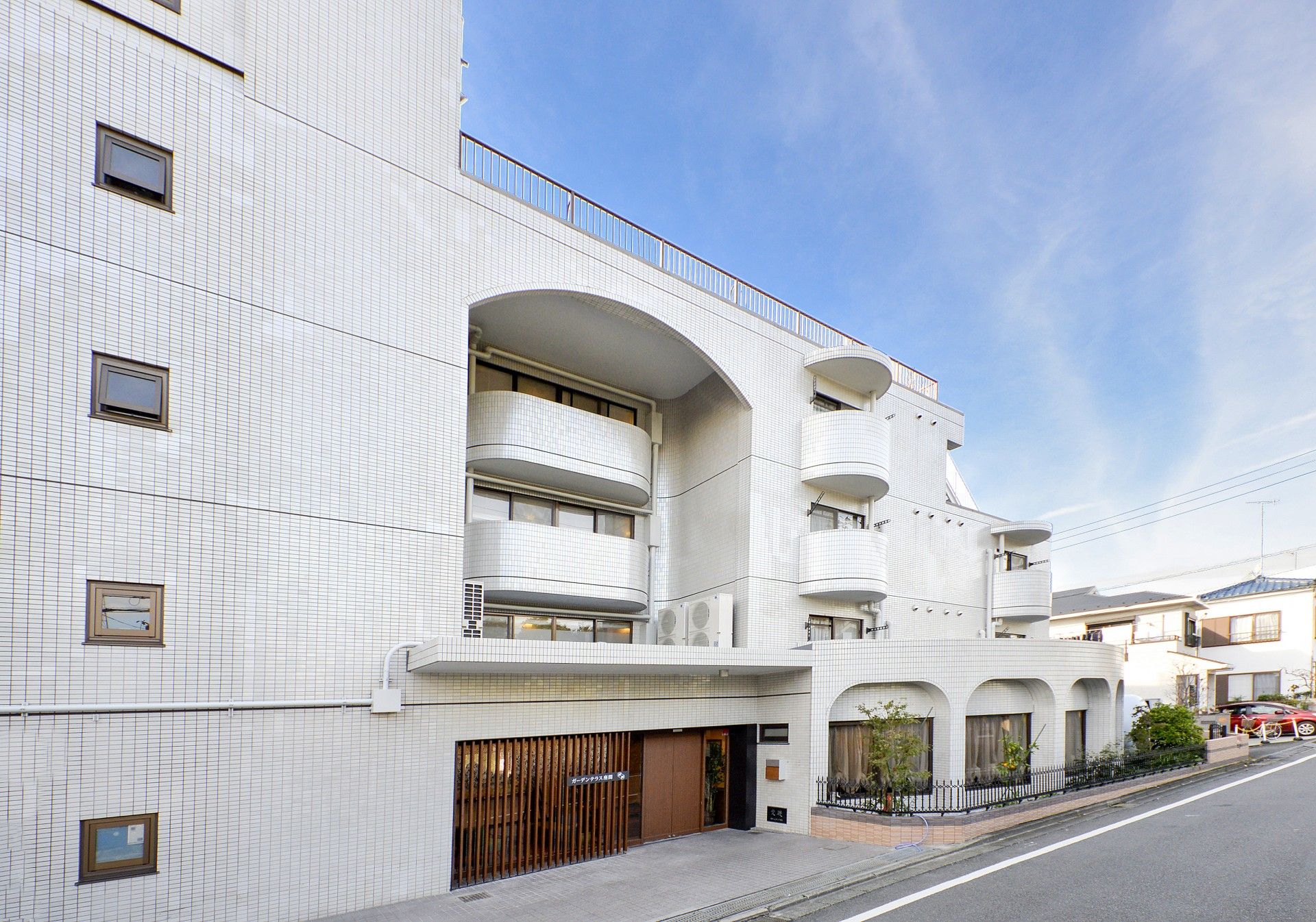 「住宅型有料老人ホーム ガーデンテラス座間」の外観。静謐な住宅地に佇む、大きめの老人ホーム。