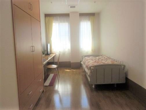 ベッドと備え付けのテーブル＆いすが置かれた居室。大きな収納スペースもある。