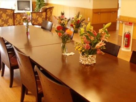 4人掛けのテーブルが二つ並んだ食堂。きれいな花が花瓶に生けられている。